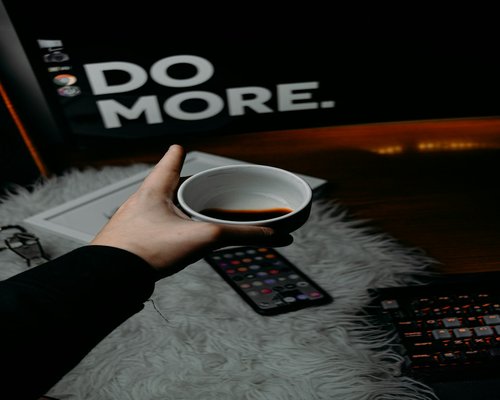 Close up of hands holding a warm cup of coffee on a tidy wooden desk
